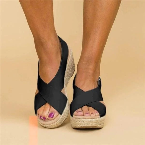 Women's black wedge platform sandals with crossover straps and an open toe, perfect for warm-weather styling.