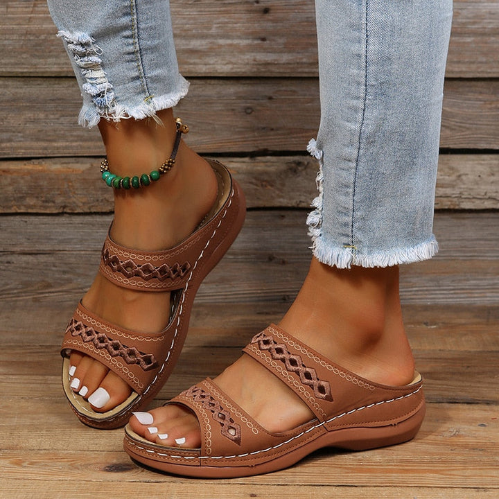 Alice women's brown double strap slide sandals with decorative cutout detailing, worn with distressed jeans.