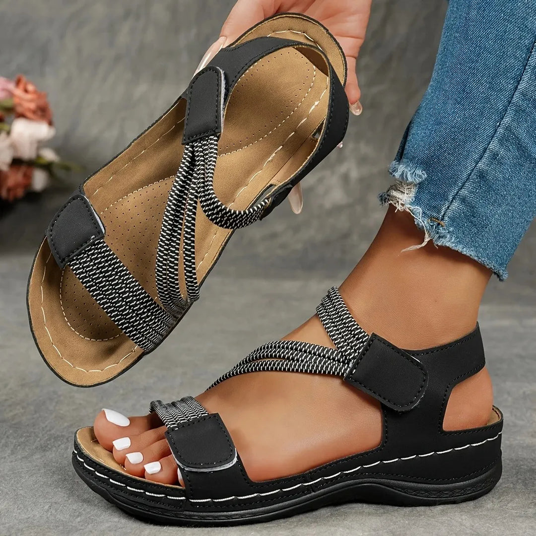 Amalyn black flat sandals with adjustable straps, contrast stitching, and open toe, perfect for warm weather.