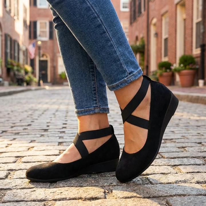Clara black orthopedic wedge strap flats with a closed toe and secure cross-strap design for everyday comfort.