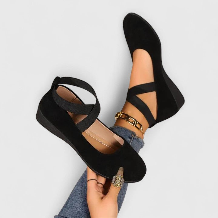 Clara black orthopedic wedge strap flats with a closed toe and secure cross-strap design for everyday comfort.
