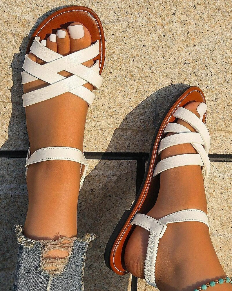 Women's Corinne white cross strap flat sandals with a flexible back strap and brown sole, perfect for summer.