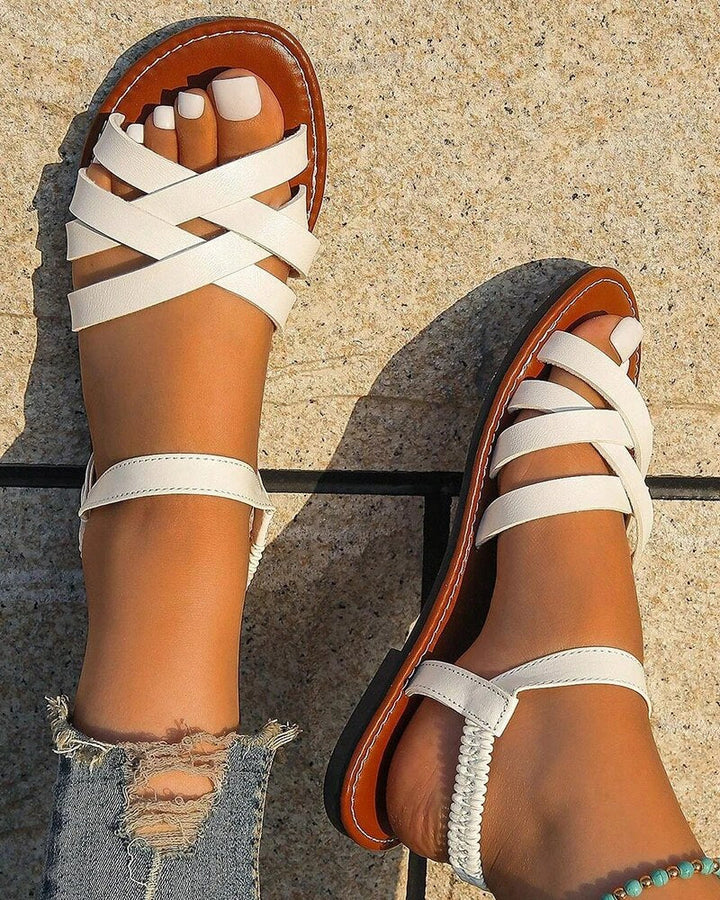 Women's Corinne white cross strap flat sandals with a flexible back strap and brown sole, perfect for summer.