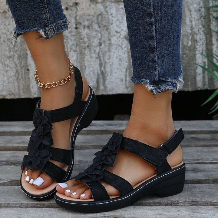 Loveleen black floral wedge sandals with adjustable strap, offering gentle height and a feminine touch.