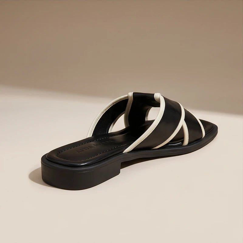 Black leather Nerissa cross strap slide sandals with white contrast trim and a modern square toe.
