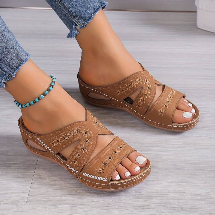 Women's Soleva embroidered wedge slide sandals in brown with side cutouts and a low wedge sole.