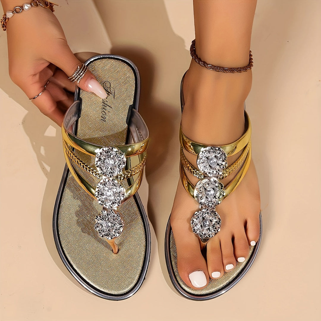 Vespera women's metallic gold thong sandals with sparkling rhinestone floral accents and a flat sole.