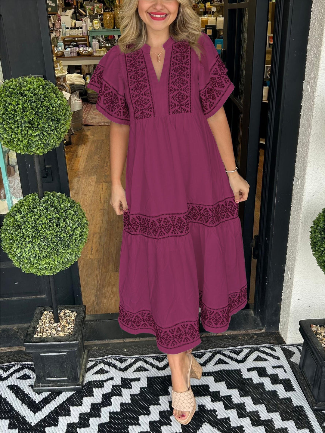 Woman in a plum Abigail boho V-neck midi dress with black embroidered details, short sleeves, and tiered skirt.