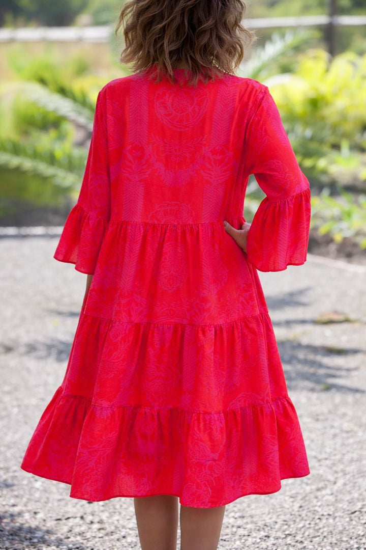 Woman in a bright red Agnes tiered boho V-neck dress with bell sleeves and a subtle pattern.