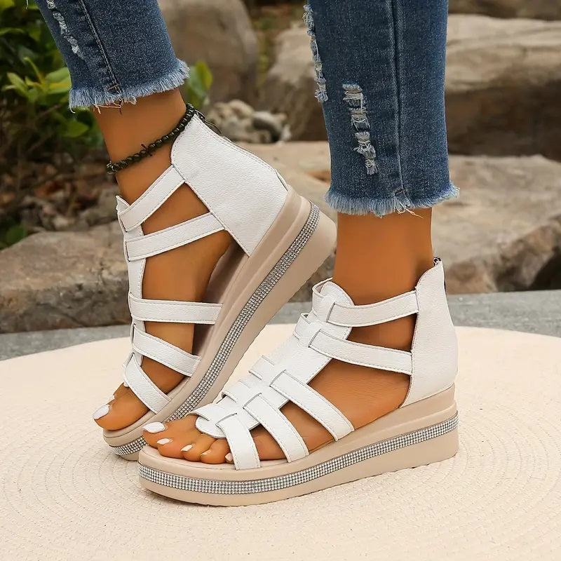 White platform gladiator sandals with strappy upper, open toe, and rhinestone-embellished beige wedge sole.