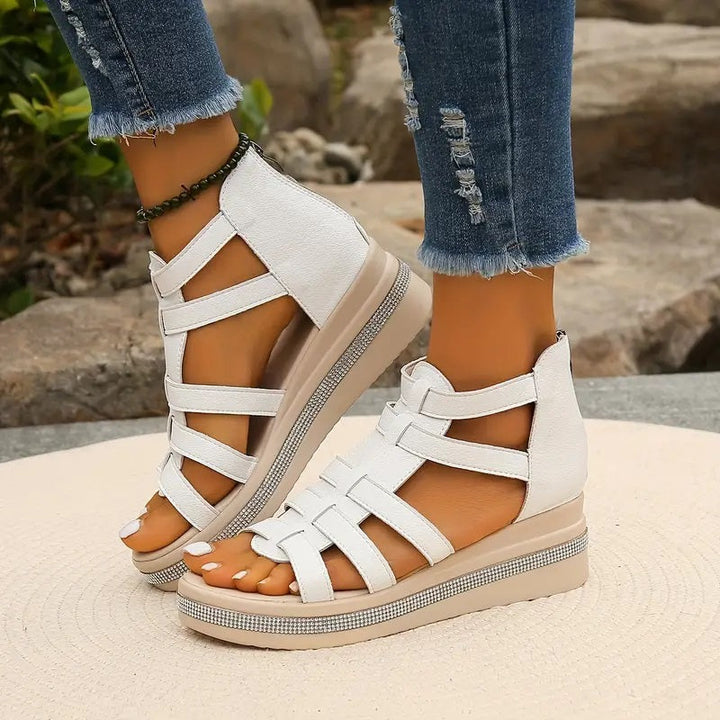 White platform gladiator sandals with strappy upper, open toe, and rhinestone-embellished beige wedge sole.