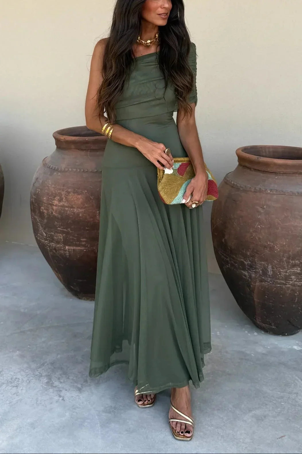 Aviana women's olive green one-shoulder maxi dress with draped bodice, flowing skirt, and gold accessories.