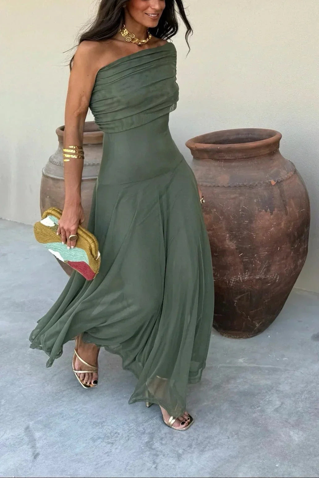 Women's Aviana one-shoulder maxi dress in olive green, with draped bodice and flowing skirt, styled with gold accessories.