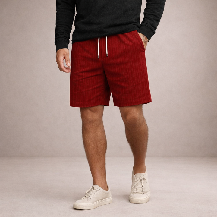 Men's Brandon red textured linen drawstring summer shorts with side pockets, worn with a black shirt and white sneakers.