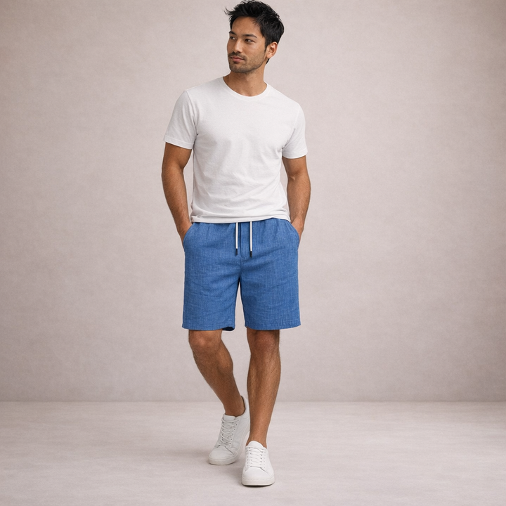 Men's Brandon blue linen drawstring shorts with side pockets, styled with a white tee and sneakers.