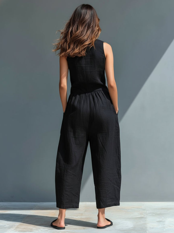 Woman from behind wearing a black linen blend sleeveless wide-leg Cassia jumpsuit with front pockets.