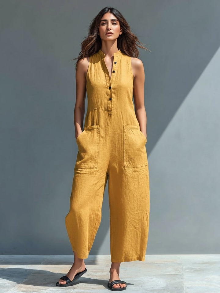 Woman in a mustard linen blend sleeveless button-up wide-leg jumpsuit with front pockets and a stand collar.