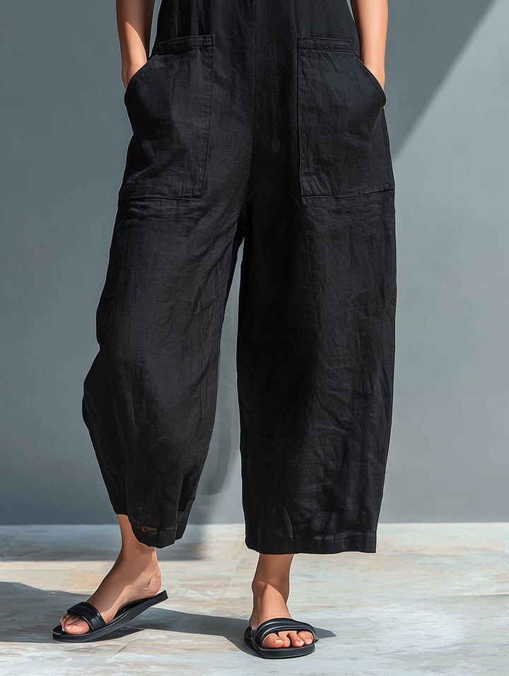 Black linen blend wide-leg jumpsuit with front pockets and button-front detail, styled with black sandals.