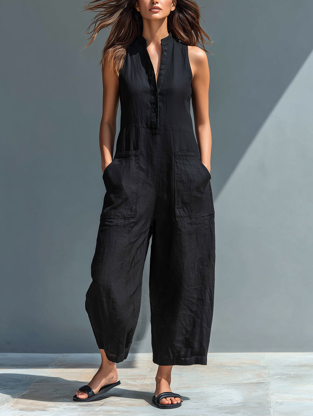 Woman in black linen blend sleeveless button-up wide-leg Cassia jumpsuit with front pockets.
