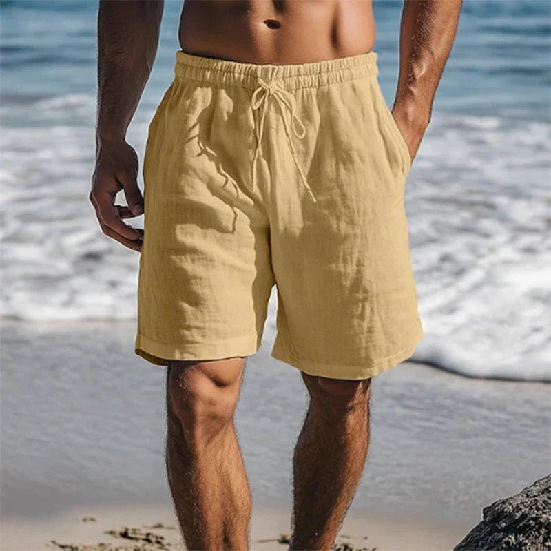 Men's Christian tan linen drawstring shorts with side pockets on a beach.