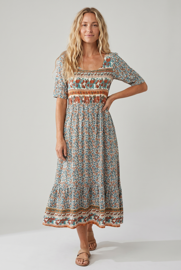 Woman in a square neck boho printed midi dress with a shirred bodice and tiered skirt.