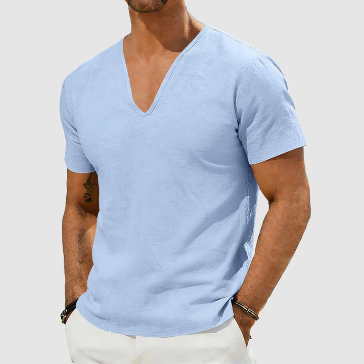 Men's light blue Declan short sleeve linen V-neck shirt, worn with white trousers.