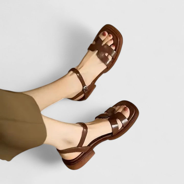 Brown women's ankle strap flat sandals with an open toe and faux leather finish.