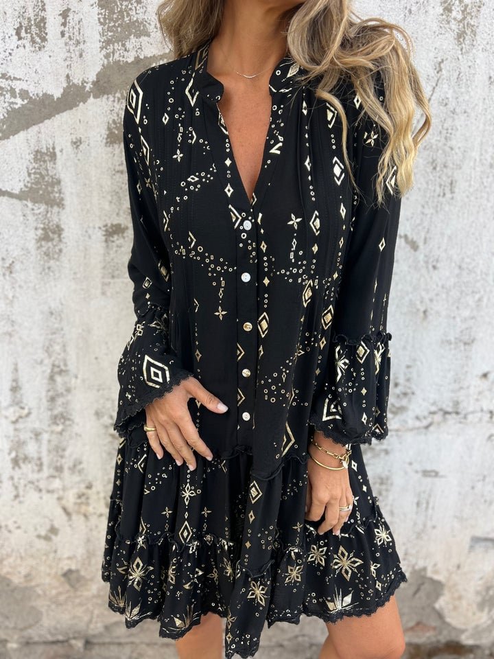 Black tiered boho V-neck dress with gold metallic print, three-quarter sleeves, and ruffled cuffs.
