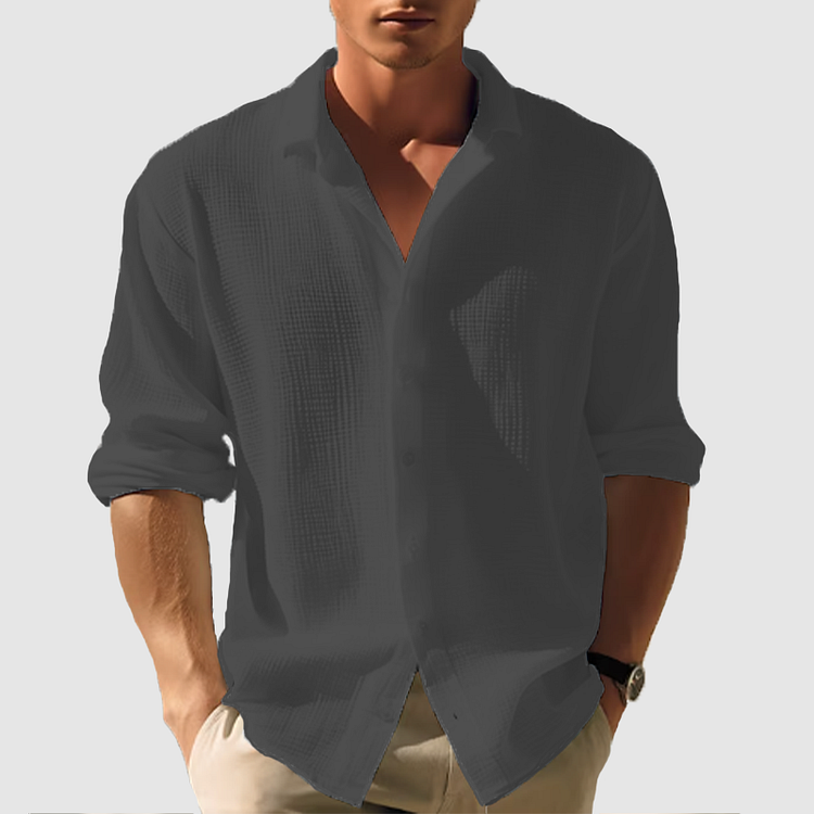 Men's dark gray linen button-up shirt with rolled sleeves, worn open over a light undershirt.