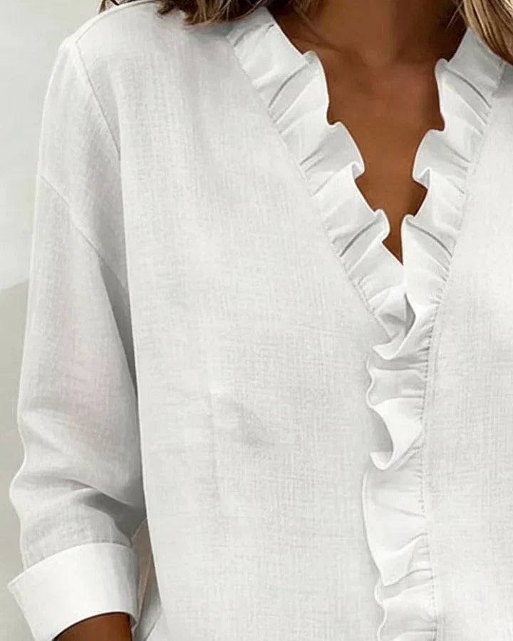 White women's V-neck ruffle blouse with long sleeves, featuring a relaxed fit.