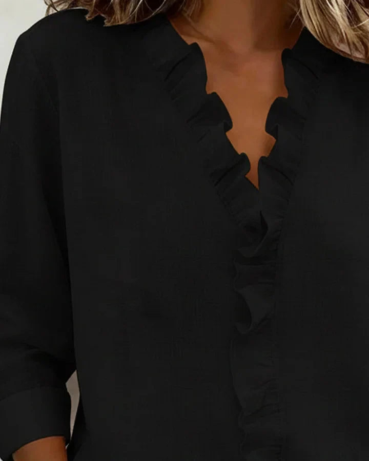 Women's white V-neck ruffle blouse with long sleeves, made from a lightweight fabric.