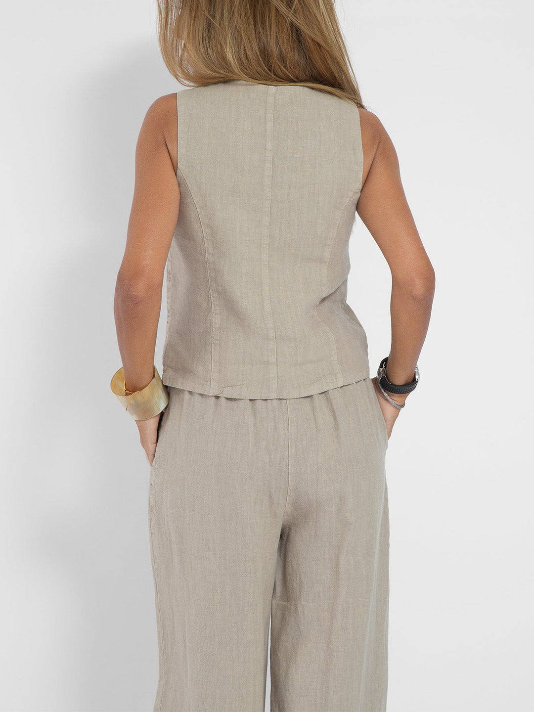 Woman from behind wearing a beige linen sleeveless V-neck vest and wide-leg pants set.