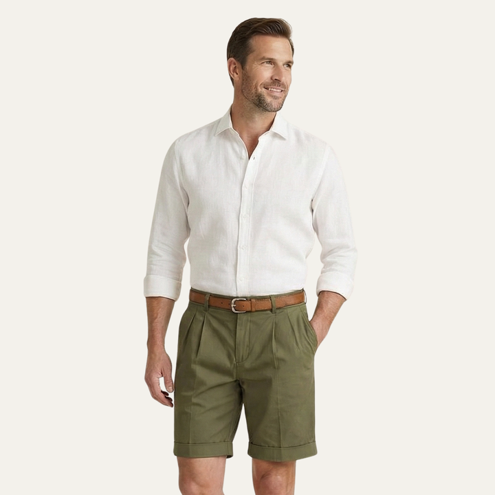 Men's Julian pleated chino shorts in olive green with a brown belt, paired with a white linen shirt.