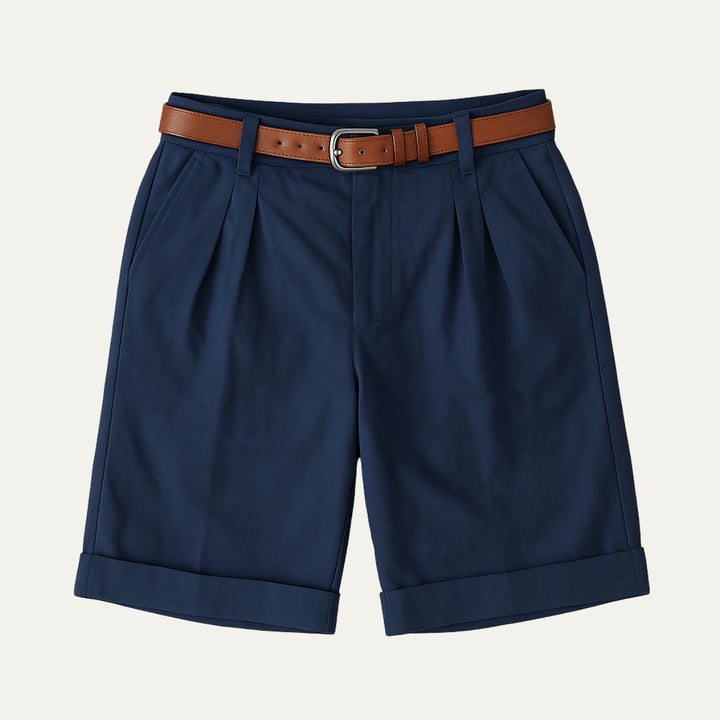 Men's Julian navy pleated chino shorts with a brown leather belt, cuffed hems, and side pockets.