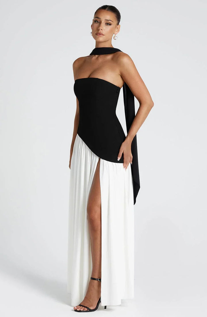 Black strapless corset maxi dress with a high slit, made from a sleek, flowing fabric.