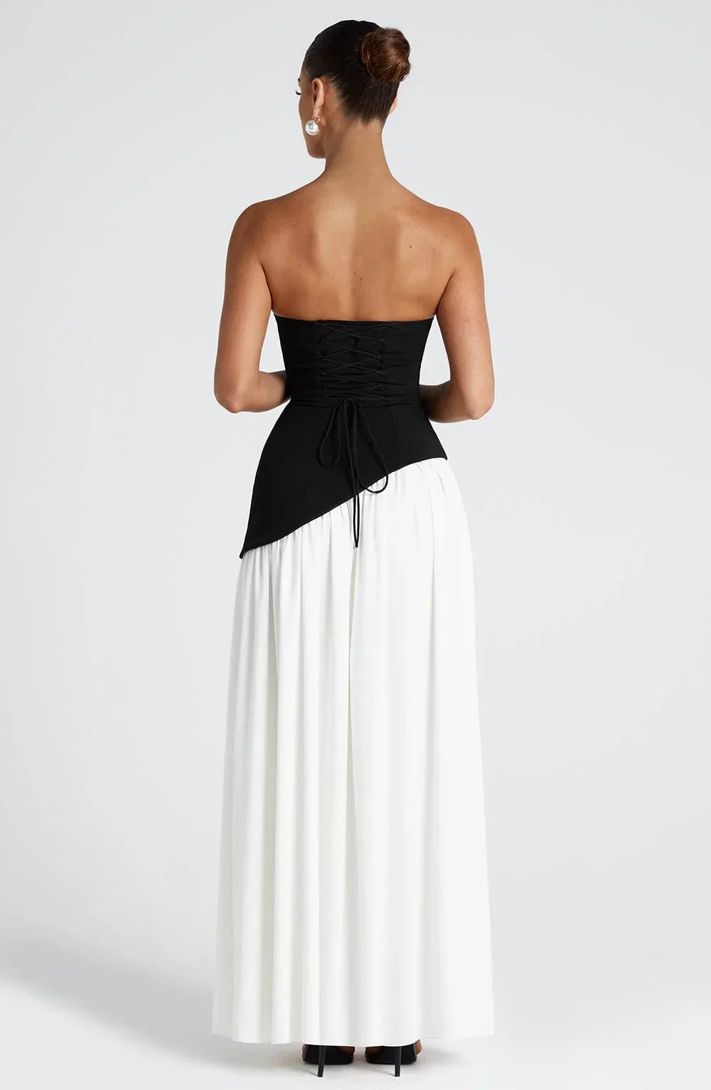 Black strapless corset maxi dress with a high slit, made from a sleek, form-fitting fabric.
