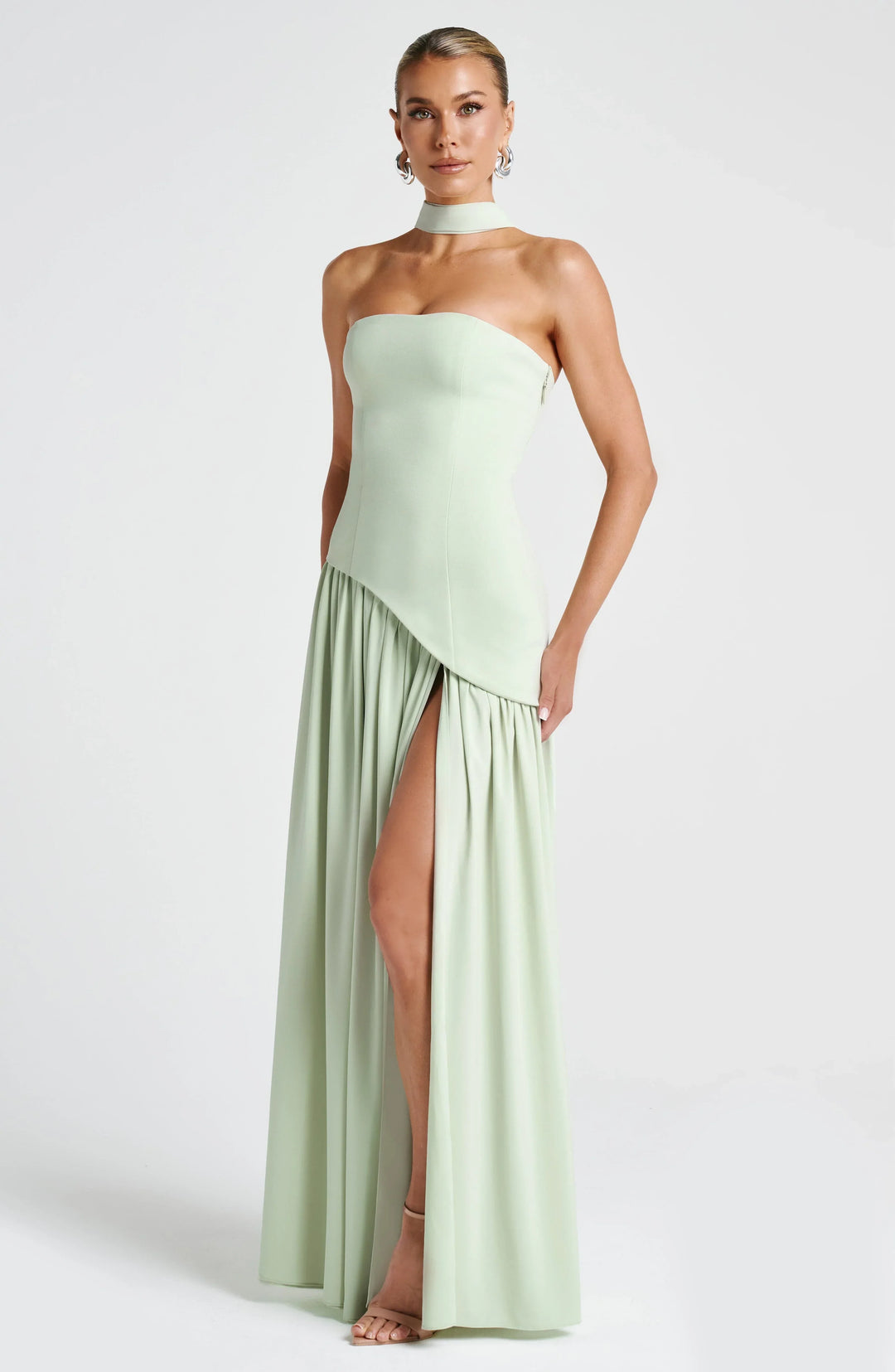 Black strapless corset maxi dress with a high slit, made from a sleek, flowing fabric.