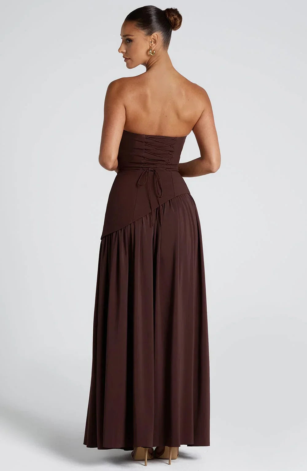 Black strapless corset maxi dress with a high slit, made from a sleek, form-fitting fabric.