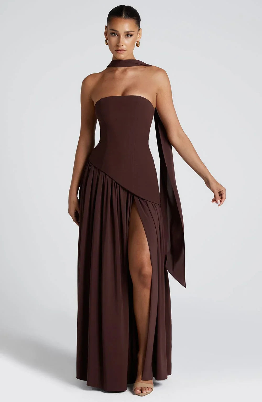 Brown strapless corset maxi dress with a high slit, made from a sleek, flowing fabric.