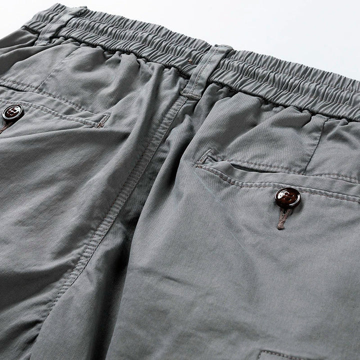 Close-up of gray men's drawstring cargo shorts with elastic waist and buttoned back pockets.