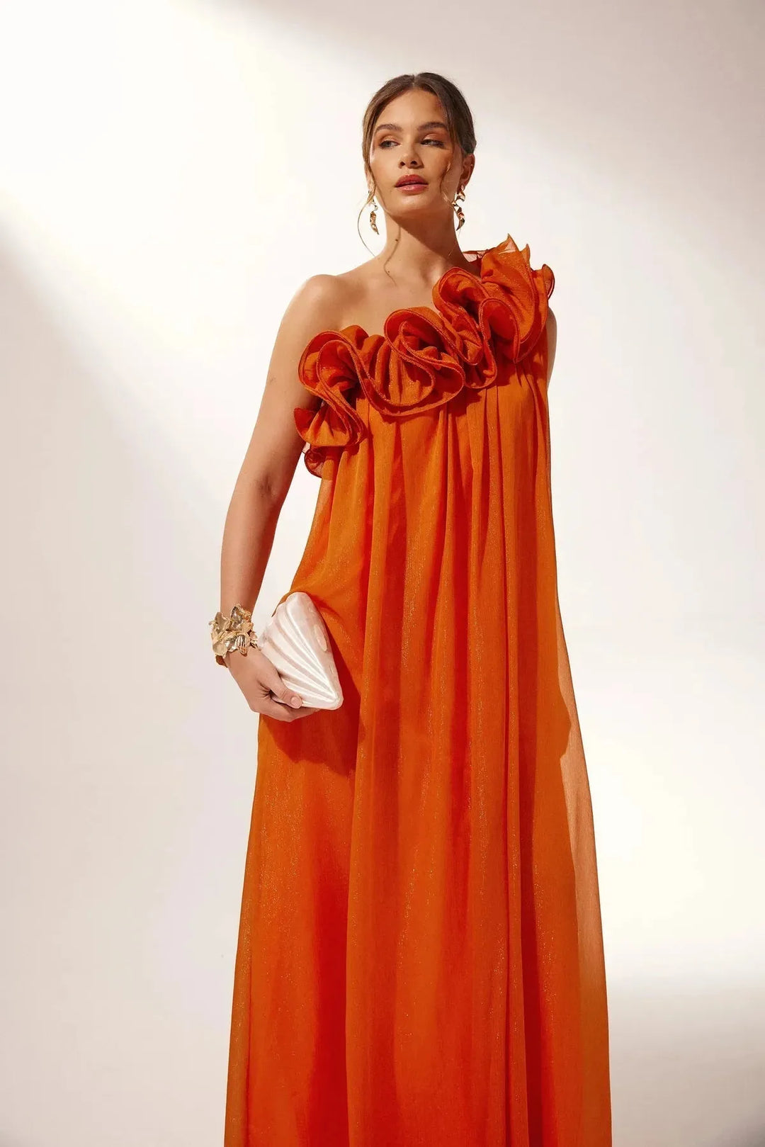 Orange one-shoulder ruffle maxi dress in a flowing fabric.