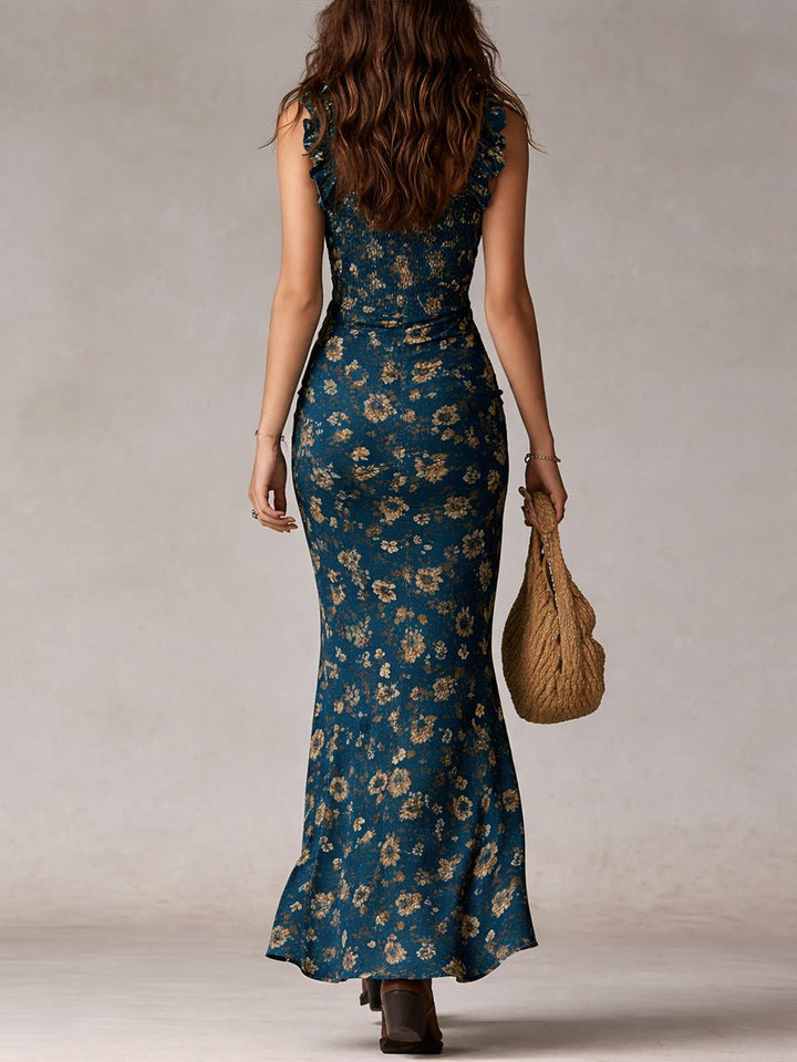 Woman from behind wearing a teal floral smocked ruffle maxi boho dress and carrying a woven bag.