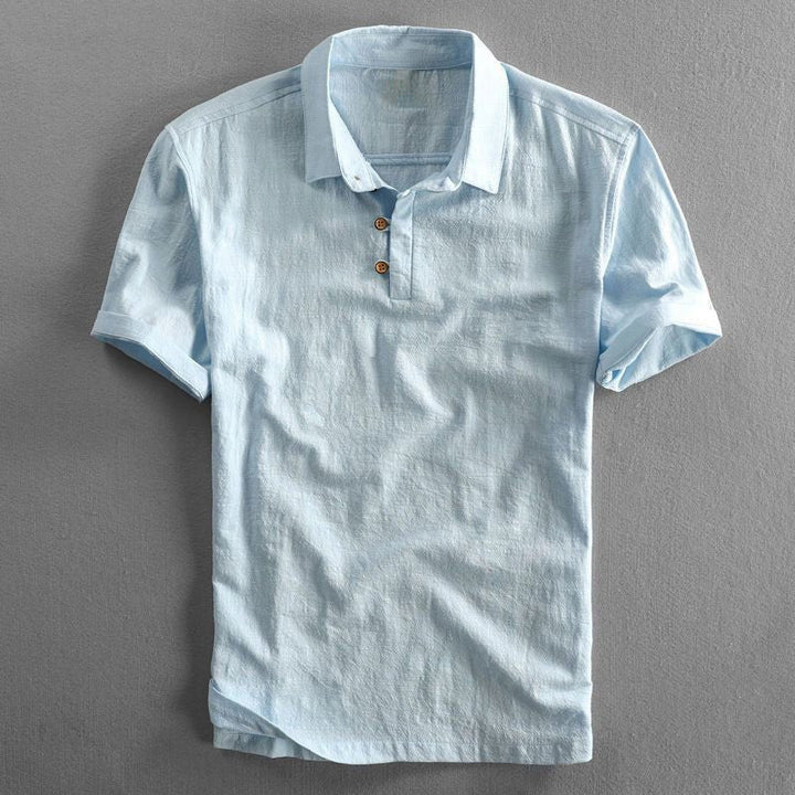 Men's light blue short-sleeve Troy polo shirt with a classic collar, button placket, and textured fabric.