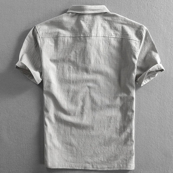 Back view of a light gray men's short sleeve polo shirt with a textured fabric and classic collar.