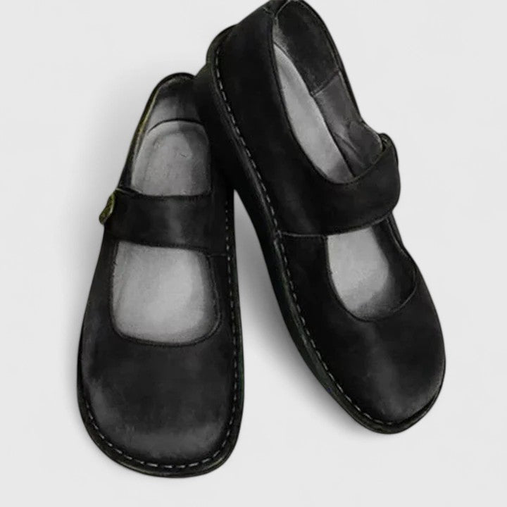 Black leather orthopedic Mary Jane shoes with adjustable strap.