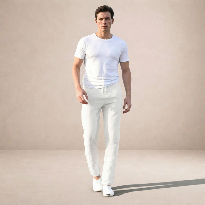 Man in white linen straight-leg summer pants with drawstring waist and a white t-shirt, walking forward.