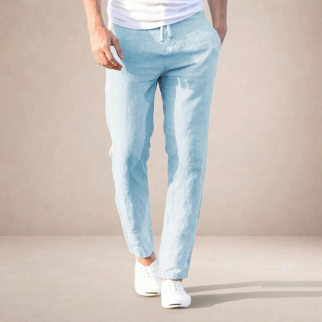 Men's light blue linen summer pants with a straight leg, drawstring waist, and side pockets, paired with white sneakers.