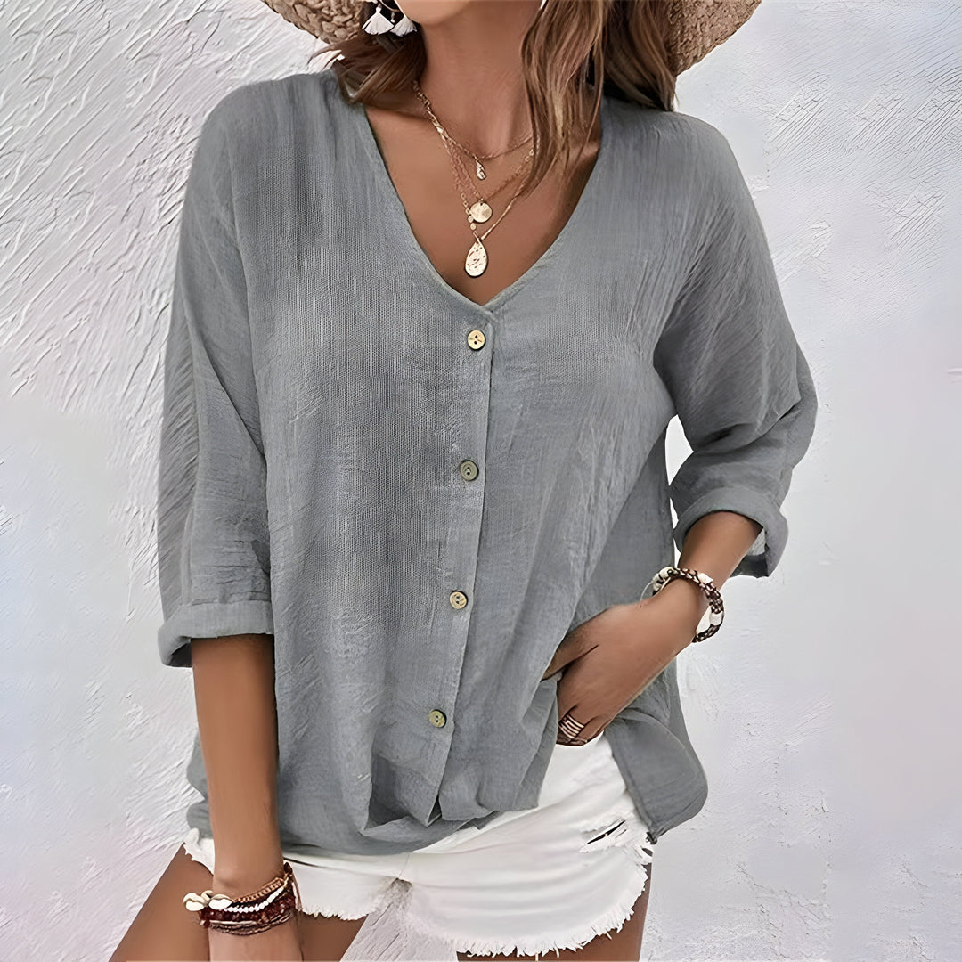 Women's white V-neck button-up blouse with long sleeves, made from a light, flowing fabric.
