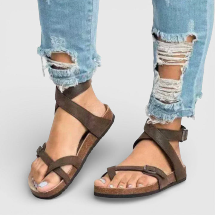Women's Zadie ankle strap flat sandals in brown, featuring crossover straps, adjustable buckles, and a cork sole.